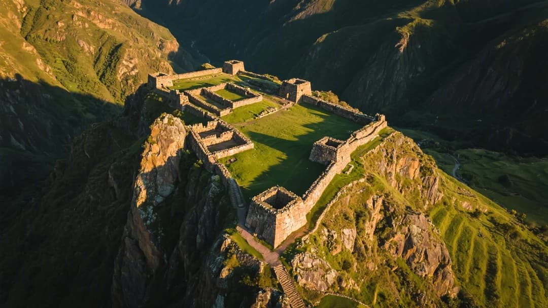 Vista aérea de las ruinas de Huacra Pucara en Cusco mostrando sus estructuras de piedra integradas en el paisaje montañoso.